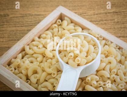 Food and Cuisine, Uncooked and Dried Elbow Macaroni or Gomiti Pasta in Plastic Measuring Cup. Stock Photo