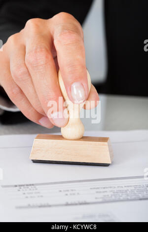 Close-up Of Business Man Hand Pressing Rubber Stamp On Document Stock Photo