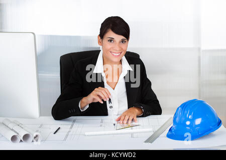 Young Happy Female Architect Working On Blue Print In Office Stock Photo