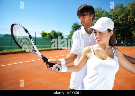 Woman and male tennis instructor practicing racket control on tennis court Stock Photo
