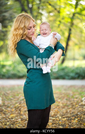 mother with crying baby in park Stock Photo