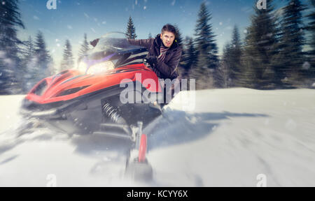young man driving  snowmobile at beautiful winter day - in motion Stock Photo