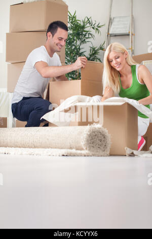 Merry young couple unpacking boxes in their new house Stock Photo