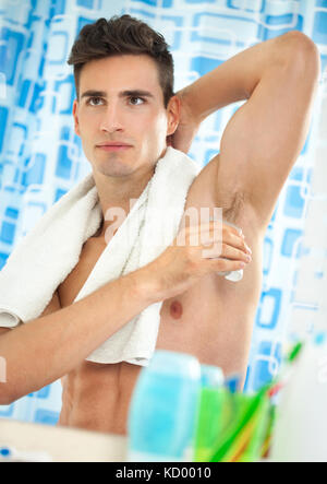 Young handsome men applying deodorant on armpits Stock Photo