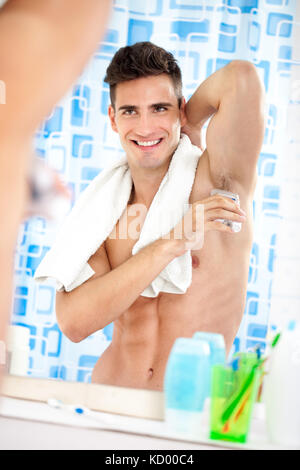 young handsome man applying roll-on antiperspirant on armpit Stock Photo