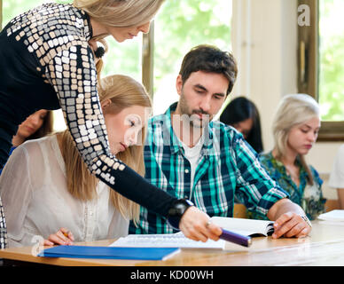 Teacher helping students with assignment Stock Photo