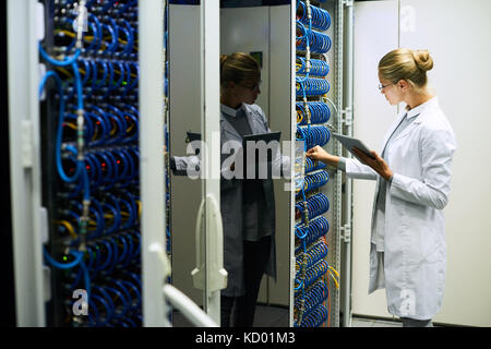 Portrait of young woman wearing lab coat working with servers in supercomputer research center, copy space Stock Photo