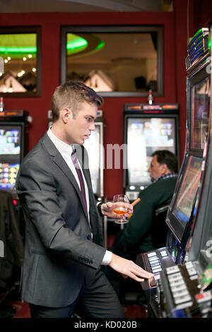 Handsome young gambling man on the slot machine in casino Stock Photo