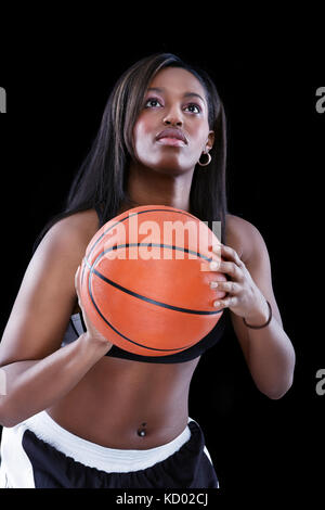 Portrait of an African American woman  basketball player playing against black  background Stock Photo