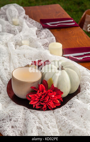 Seasonal table centerpiece setting of a pumpkin, candle and flower. Stock Photo