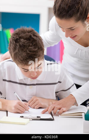 young boy doing homework with assistance of his sister Stock Photo