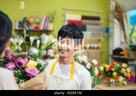 Male florist offering flowers at the counter in the florist shop Stock Photo