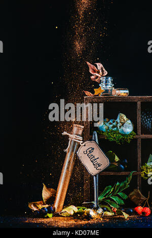 Mystic still life with a test tube of stardust and wooden case with magical items and potion ingredients. Wizard or witch table with pixie dust. Fairy tale concept with dark background and copy space. Stock Photo