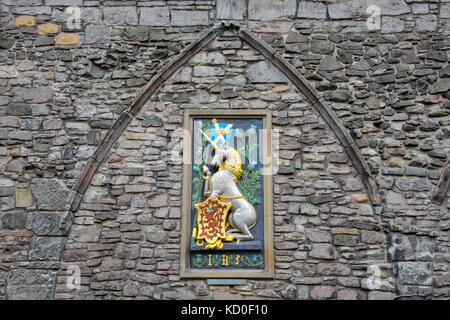 Unicorn with the Scottish flag and an emblem with a red lion on gold on a stone wall Stock Photo