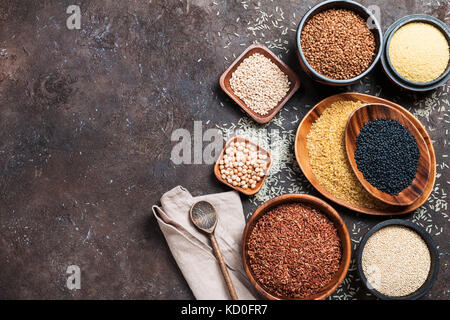 assortment of different cereals and seeds in bowl on dark brown background, top view Stock Photo
