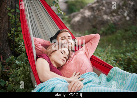 Couple relaxing in hammock, eyes closed sleeping, Krakow, Malopolskie, Poland, Europe Stock Photo