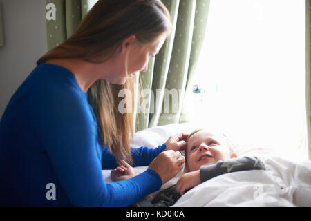 Boy lying in bed gazing at mother Stock Photo