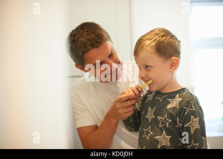 Mature man showing son how to brush teeth in bathroom Stock Photo