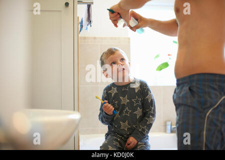 Boy in bathroom with father preparing to brush teeth Stock Photo