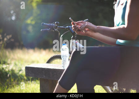 Cyclist taking break, using mobile phone Stock Photo