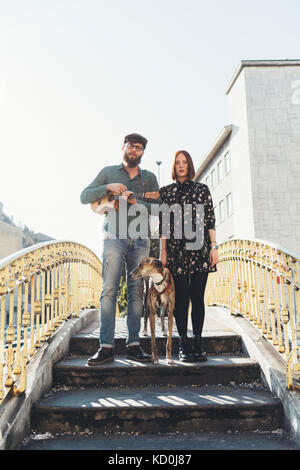 Portrait of cool couple with dog standing on footbridge Stock Photo
