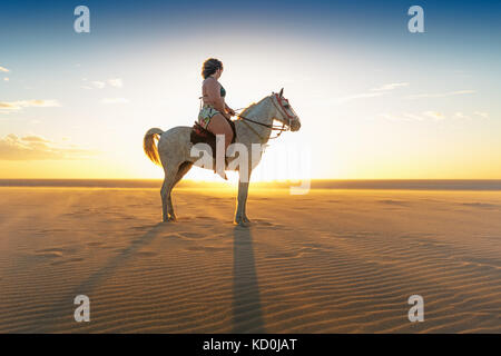 Woman riding horse on beach, side view, Jericoacoara, Ceara, Brazil, South America Stock Photo