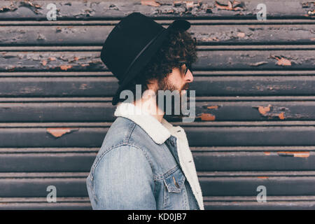 Profile of young man, standing in front of shutter Stock Photo
