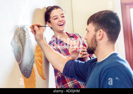 Couple painting wall mural smiling Stock Photo