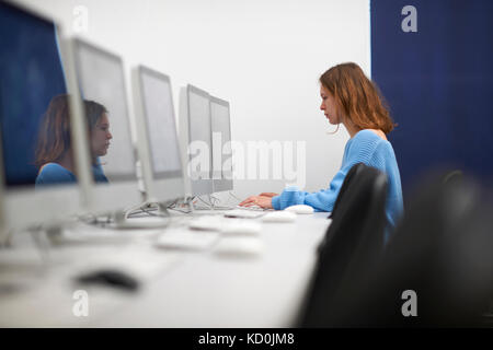 Young female college student typing on computer keyboard in classroom Stock Photo