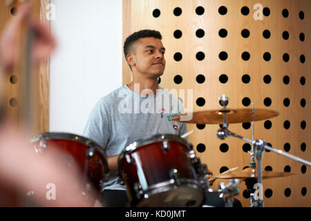Young male college student playing drums in recording studio Stock Photo
