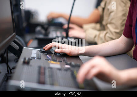 Hands of male and female college students at mixing desk in TV studio Stock Photo