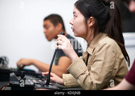 Young male and female college students at mixing desk in TV studio Stock Photo
