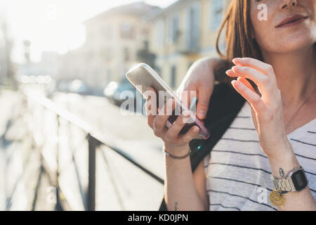 Cropped shot of couple on sidewalk looking at smartphone Stock Photo