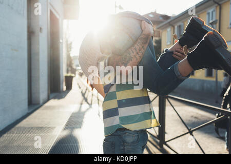 Man carrying girlfriend over his shoulder on sidewalk Stock Photo