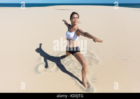 Woman on beach arms open stretching in yoga position Stock Photo