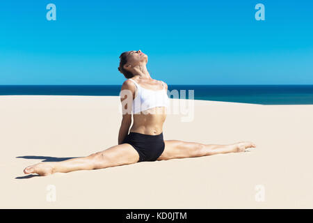 Woman on beach in yoga position, the splits Stock Photo