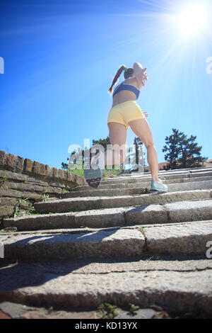 woman running by steps on sunny day Stock Photo