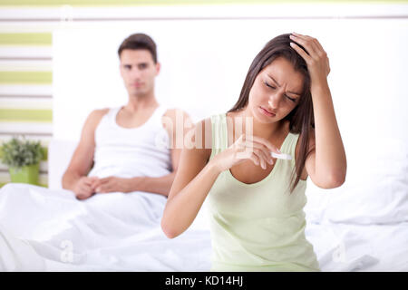 Distressed couple finding out results of a pregnancy test in the bedroom Stock Photo