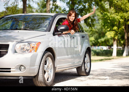 Happy woman in car waving out the window Stock Photo