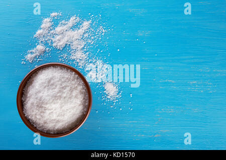 Clay brown bowl with salt on blue background Stock Photo