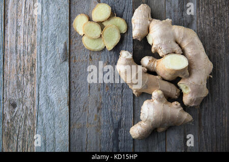 Ginger root and slices on rustic boards viewed from directly above. Stock Photo