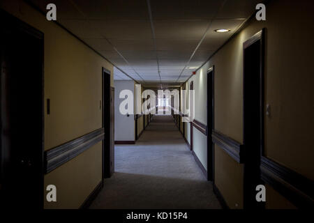 Dark hotel lobby with rooms on both sides of the corridor taken in a 70's designed hotel.   Picture of a dark hotel lobby from the 70's taken during t Stock Photo