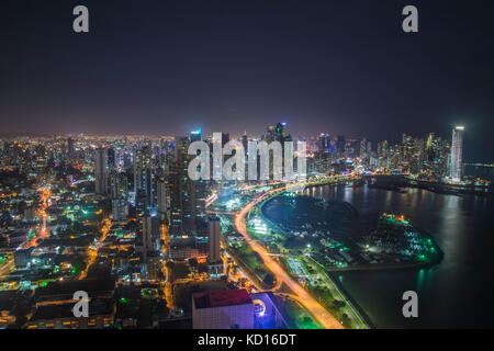 The blue light of dusk illuminates a block of high rises over the streaking red tail lights of speeding cars on Balboa Avenue in Panama City. The stre Stock Photo