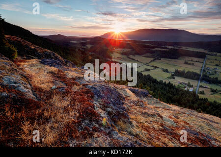 The sun rises over the Mount Constitution and the Crow Valley, viewed from Ship Peak on Turtleback Mountain, Orcas Island, Washington, USA Stock Photo