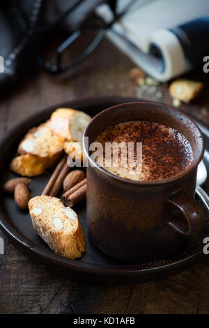 Cup of cappuccino coffee with Italian cantuccini almond biscuits for breakfast on dark rustic wooden background Stock Photo