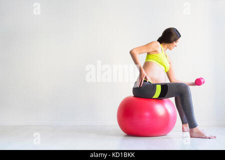One young pregnant woman doing fitness exercises at studio Stock Photo