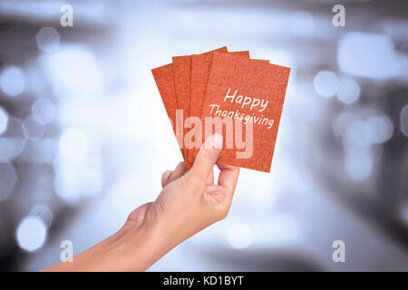 Human hand holding Happy Thanksgiving card against abstract background Stock Photo