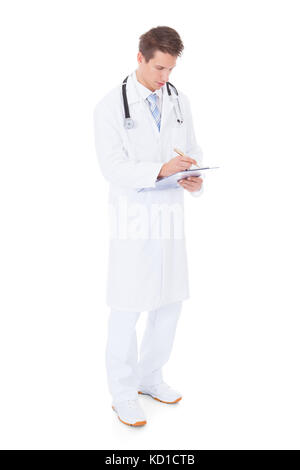 Young Male Doctor Holding Clipboard Standing Over White Background Stock Photo
