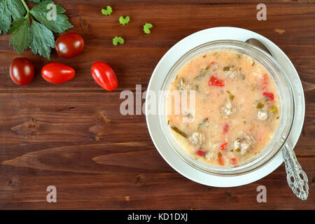 Top view of a delicious homemade meatballs soup with tomatoes, celery and rice on a wooden table. Traditional bulgarian cuisine (Supa Topcheta) Stock Photo