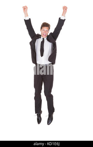 Excited Young Businessman With Arm Raised Standing On White Background Stock Photo